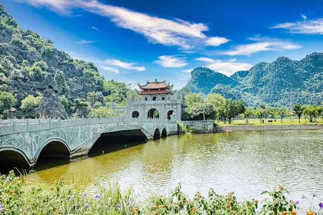 Hoa Lu Ancient Capital with river views, lush greenery, and clear blue sky, surrounded by scenic natural landscape