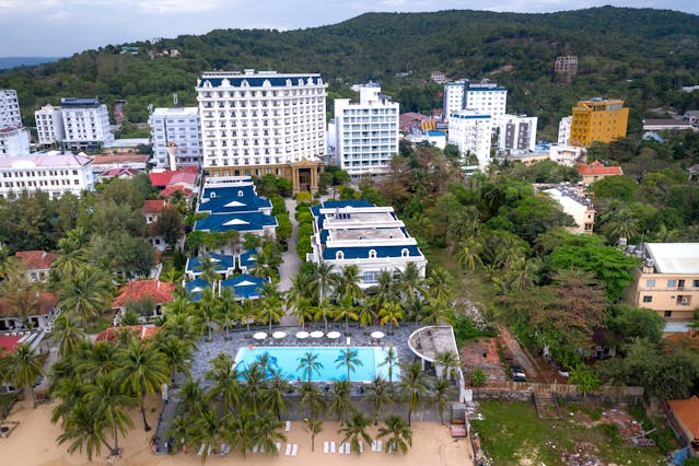 Aerial view of a beach resort surrounded by greenery and coastline with the sea in the background.